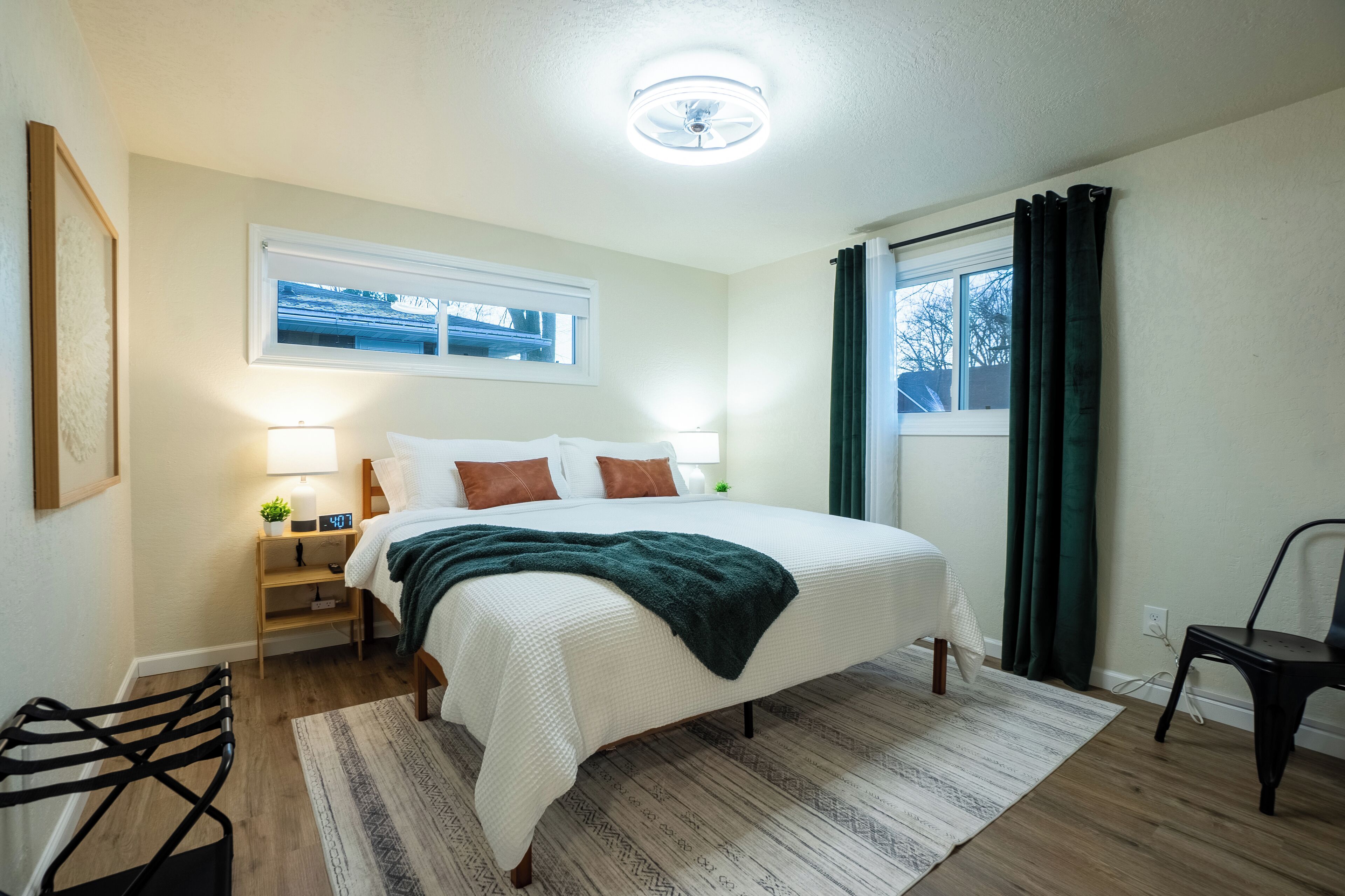 A bedroom with a bed, bedside table, lamp, and a window with curtains.