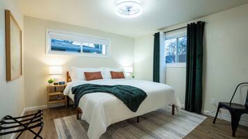 A bedroom with a bed, bedside table, lamp, and a window with curtains.