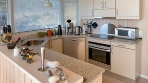 Una cocina moderna con encimera de granito, electrodomésticos de acero inoxidable y armarios de madera.