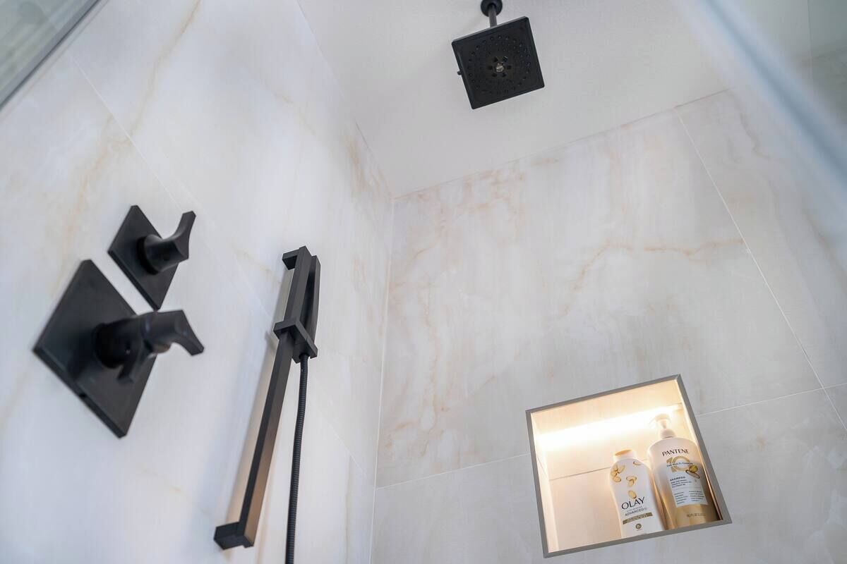 Een badkamer met een douche, een handdoekhouder en een plank met toiletartikelen.