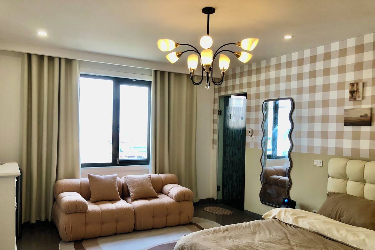 A modern bedroom with a sofa, bed, and a unique mirror.