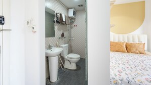 Une salle de bain avec des toilettes, un lavabo et une douche, et une chambre avec un lit et des oreillers.