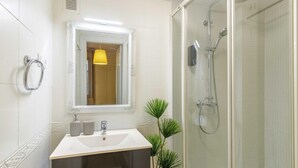 Et moderne badeværelse med et glasvægshus, et spejl og et vækstpotteplante.