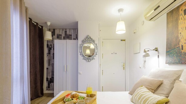 Et hotelværelse med en seng, bakke med morgenmad, garderobeskab, dør og et billede på væggen.
