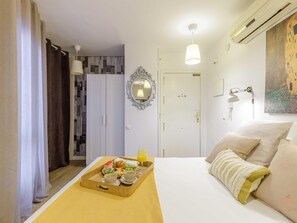 A hotel room with a bed, a breakfast tray, a wardrobe, a door, and a painting on the wall.
