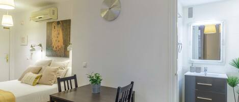 A modern bedroom with a bed, bedside table, and a wall-mounted clock.