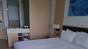 Een hotelkamer met een groot bed, een badkamer met een spiegel, een wastafel en een schilderij aan de muur.