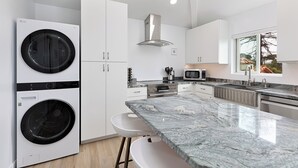 Cozinha moderna com bancada de mármore, eletrodomésticos embutidos e uma janela grande.