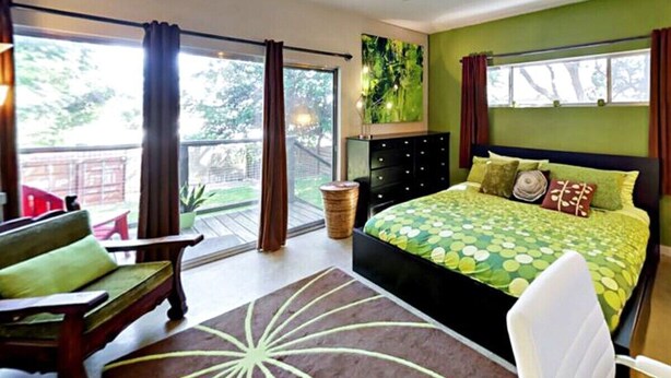 Une chambre à coucher avec un lit, une chaise, une fenêtre et un ventilateur de plafond.