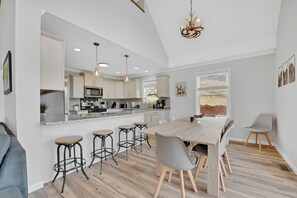 Una cocina moderna con una isla grande, taburetes de bar y una mesa de comedor con sillas.