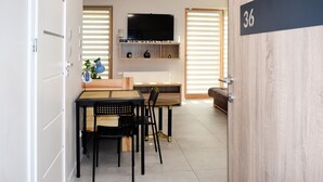 Una cocina moderna con comedor, un televisor sobre la encimera, y una puerta de madera con el número 36.
