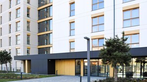Un edificio moderno de varios pisos con fachada plana, ventanas amplias y una combinación de paneles de vidrio y sólidos.