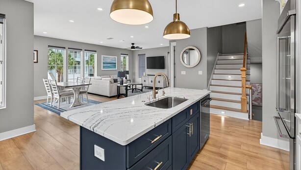 A modern kitchen with a marble countertop, stainless steel sink, and two pendant lights. - Storybook - Near Beach with Private Pool (Destin)