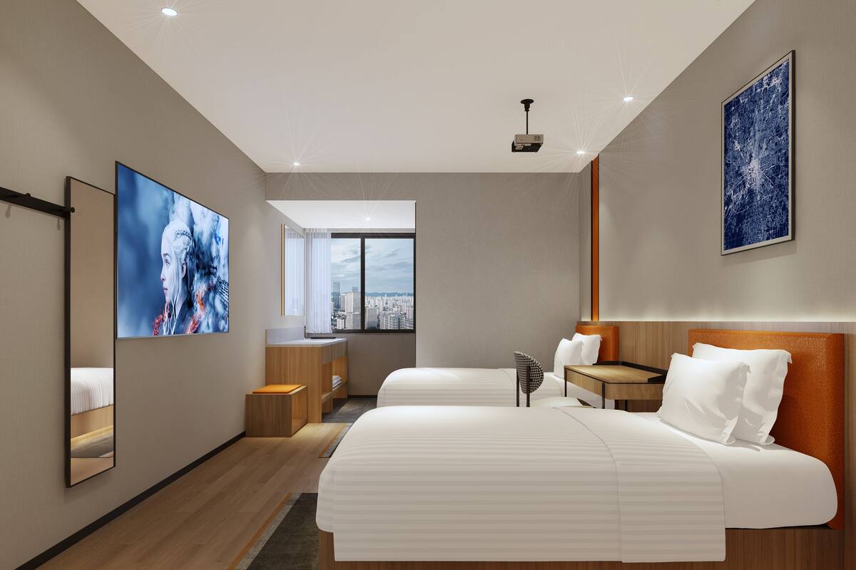 A modern hotel room with two beds, a large window with a city view, a desk, and a chair.