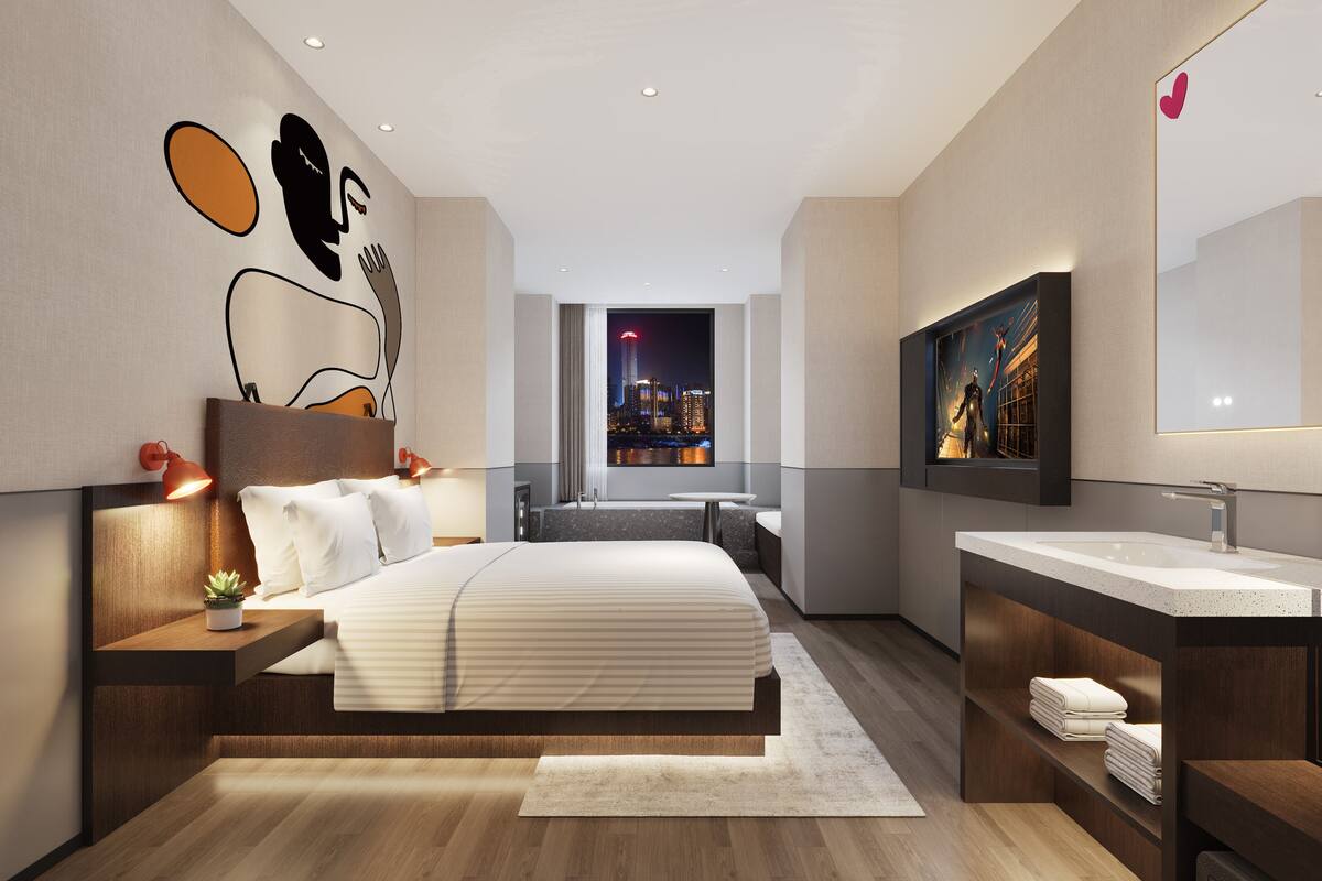 A modern hotel room with a large bed, a bathroom with a large mirror, and a city view through the window.