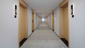 A long, narrow hallway with wooden doors and light-colored walls, featuring illuminated room numbers on the walls. - Mcsrh Hotel -Chengdu Jianshelu (Chengdu)