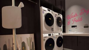 A laundry room with a large wall-mounted washing machine and dryer, a hanging rack, and a decorative wall with cacti. - Mcsrh Hotel -Chengdu Jianshelu (Chengdu)