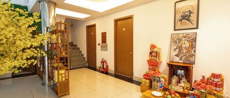A hotel lobby with a reception desk, a staircase, and a wall adorned with artwork.