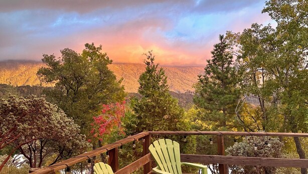 A wooden deck with two green Adirondack chairs overlooking a forested valley. - Charming Rustic Mountain Cabin, Near Yosemite,Amazing Views, and a Fireplace (Wishon)