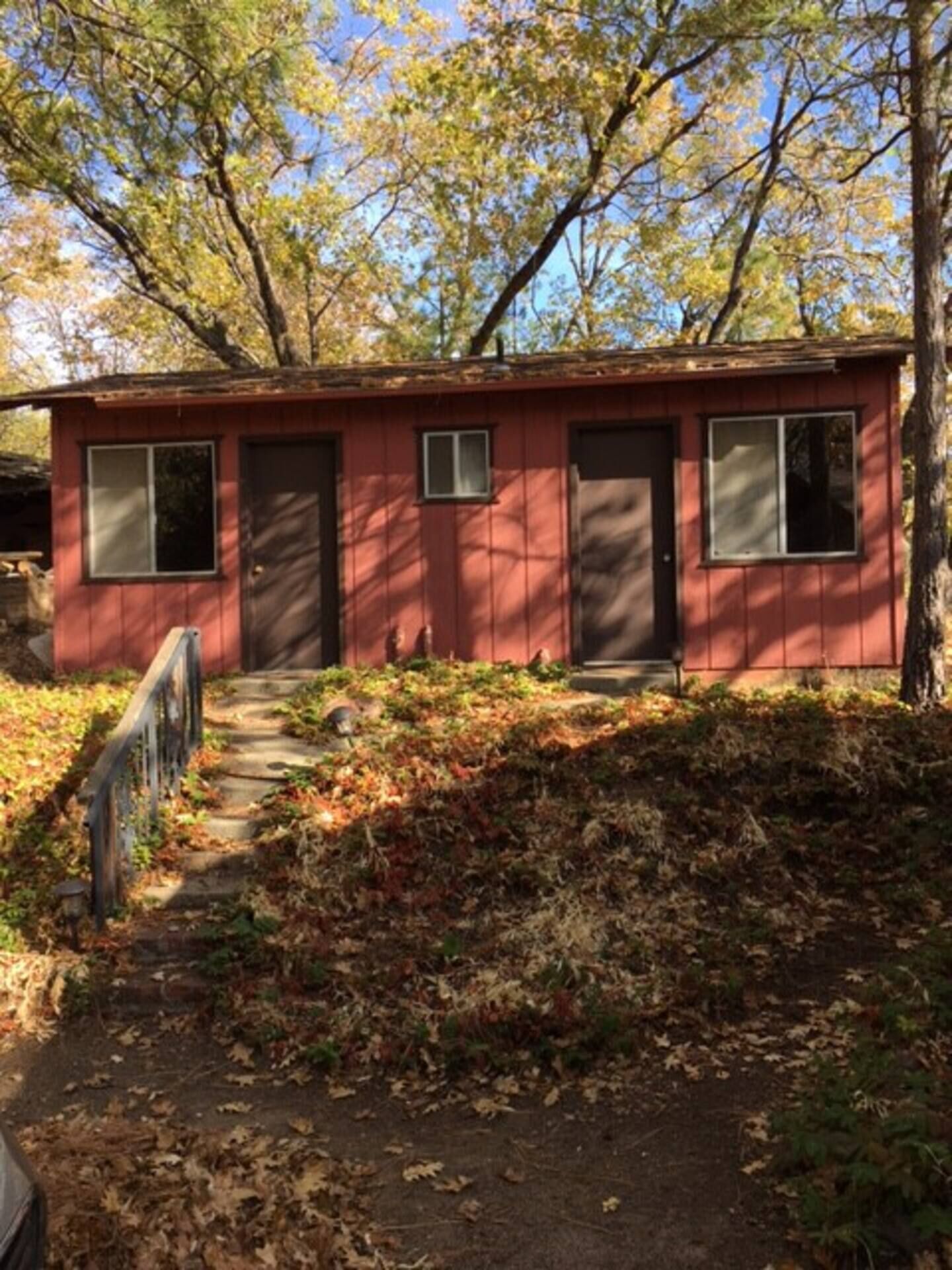A small, single-story building with a red exterior, a front door, and a small window.