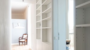 A spacious room with a wooden floor, white walls, and a large white shelving unit.