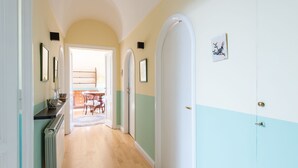 A hallway with a wooden floor, white and teal walls, and a door with a brass handle. - Babuino by Interhome (Roma: Piazza di Spagna)