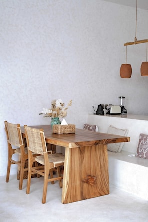 A wooden dining table with four chairs, a vase with dried flowers, and a toaster on a countertop. - Villa Serai Kedungu (Tabanan)