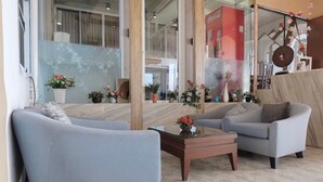 Een moderne woonkamer met twee grijze banken, een houten salontafel en verschillende potplanten.