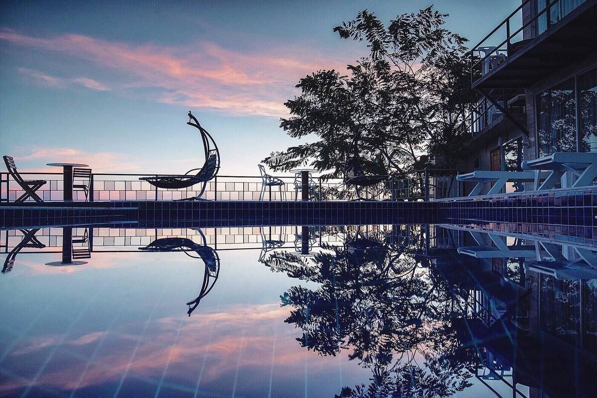 A serene outdoor area with a reflective pool, seating, and a tree.