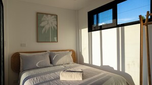 A bedroom with a bed, a window with blinds, a wooden ladder, and a framed picture on the wall. - Selah Fiji (Nadi)