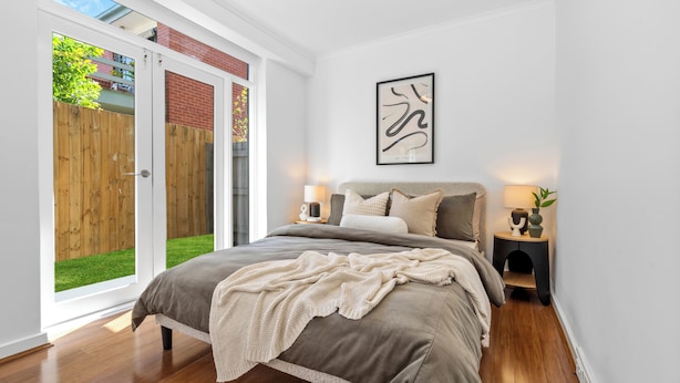 A bedroom with a bed, bedside tables, a framed artwork, and a sliding glass door to a backyard. - Balaclava City Hub by Ready Set Stay (Balaclava)