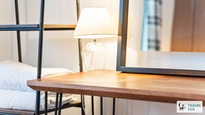 A hotel room with a wooden bedside table, a white lamp, and a large mirror. - Lime Corner: Peaceful with Parking (Leicester)