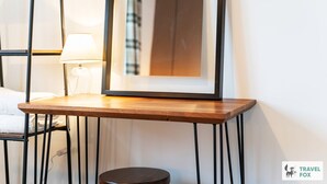 A framed picture on a wooden table, a lamp, and a bed with a white pillow. - Lime Corner: Peaceful with Parking (Leicester)