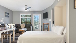 A bedroom with a large bed, a dining table with chairs, a sofa, and a TV mounted on the wall. - Lake Front Condo, Sleeps 10, Fireplace, Private Balcony, Ticket Deals, Resort Amenities, (Branson)