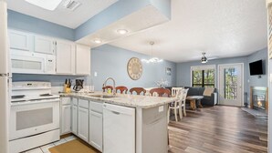 A modern kitchen with white appliances, a central island, and a dining area with a fireplace. - Lake Front Condo, Sleeps 10, Fireplace, Private Balcony, Ticket Deals, Resort Amenities, (Branson)