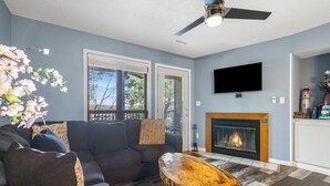 A living room with a sofa, a wooden coffee table, a fireplace, and a television mounted on the wall. - Lake Front Condo, Sleeps 10, Fireplace, Private Balcony, Ticket Deals, Resort Amenities, (Branson)