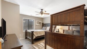 A bedroom with a bed, wooden headboard, ceiling fan, and a window with blinds. - Lavish Waterfront Condo 60ft from Table Rock Lake! (Branson)