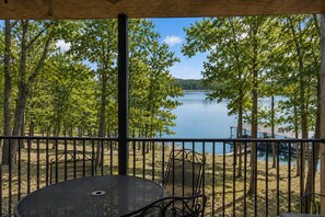 Un espacio al aire libre cubierto con una mesa y sillas, con vistas a un lago y árboles.