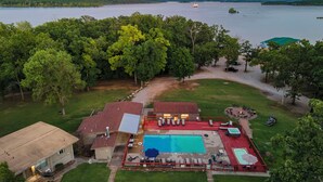 A residential property with a swimming pool, outdoor seating area, and a view of a lake. - Lakefront Condo, 2 min to Silver Dollar City! Ticket Deals & Resort Perks (Branson)