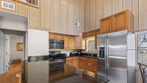 A kitchen with wooden cabinets, a stainless steel refrigerator, a microwave, and a granite countertop. - Blue Mountain Beach Getaway | Walk to Beach & Dining | Community Pool (Santa Rosa Beach)