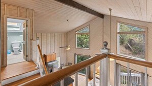 A wooden interior with a staircase, a view of the outdoors, and a bathroom visible through an open door. - Blue Mountain Beach Getaway | Walk to Beach & Dining | Community Pool (Santa Rosa Beach)