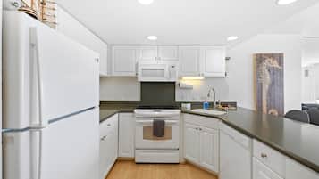 Una cocina moderna con armarios blancos, estufa, microondas y pileta.