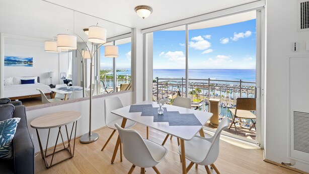 Camera d'albergo moderna con balcone, zona pranzo e letto con vista sulla città.
