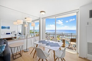 Quarto de hotel moderno com varanda, área de jantar e cama com vista para a cidade.