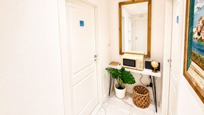 A hallway with white doors, a large mirror, a small plant, a basket, and a painting on the wall. - Vertigini Suites (Riomaggiore)
