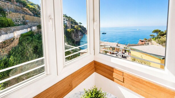 A room with a view of the sea, a stone wall, and a wooden floor. - Vertigini Suites (Riomaggiore)