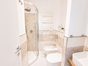 Ein Badezimmer mit Dusche, Toilette, Bidet und Waschbecken.