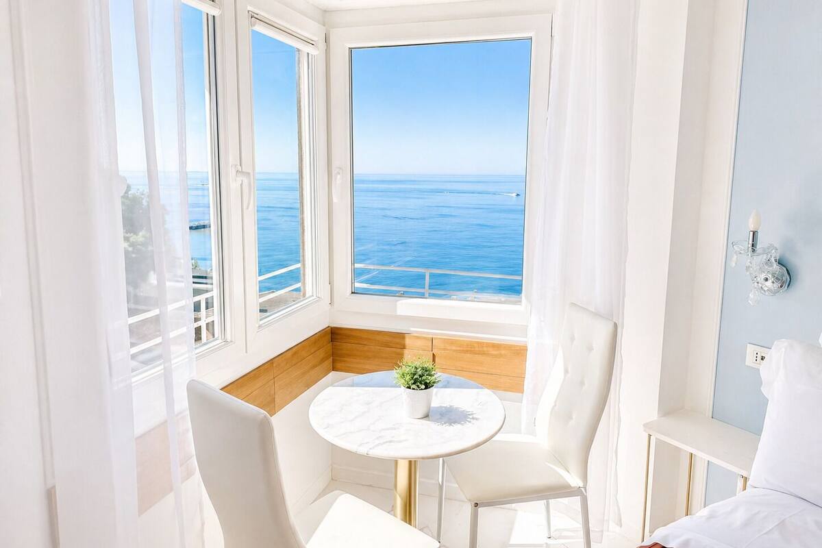 Ein Zimmer mit Meerblick, ein runder Tisch mit Stühlen und eine kleine Pflanze.