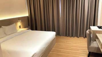 A hotel room with a bed, a desk, and curtains.