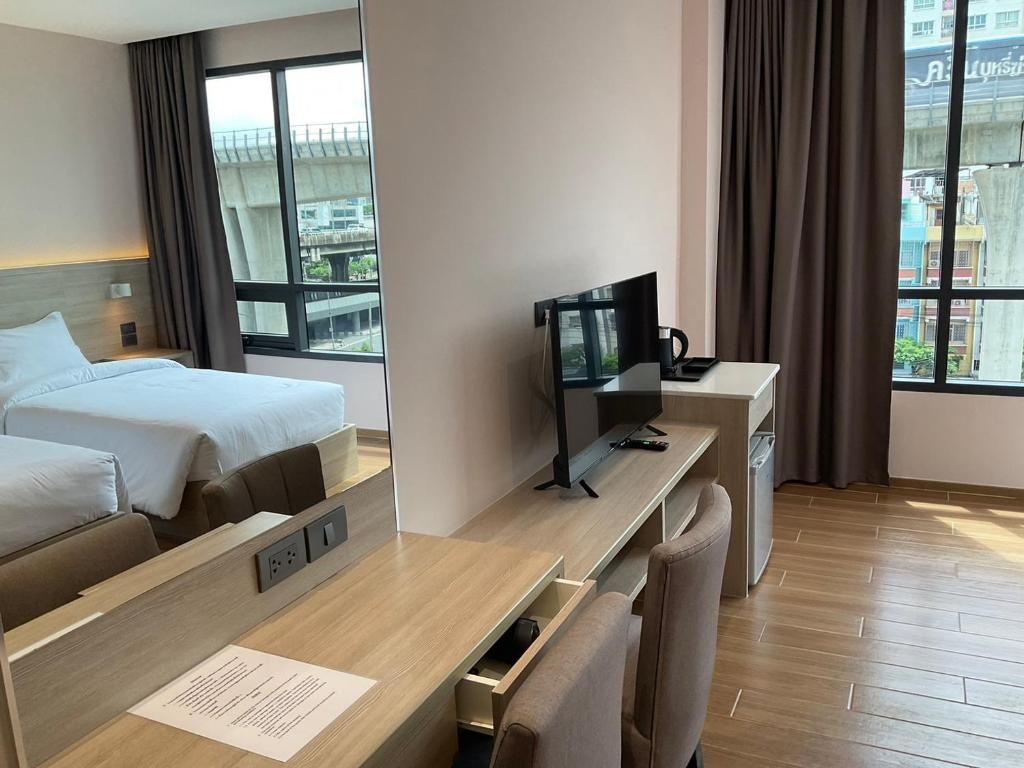 Una camera d'albergo con un letto, una scrivania con un computer, una sedia e una finestra con tende.